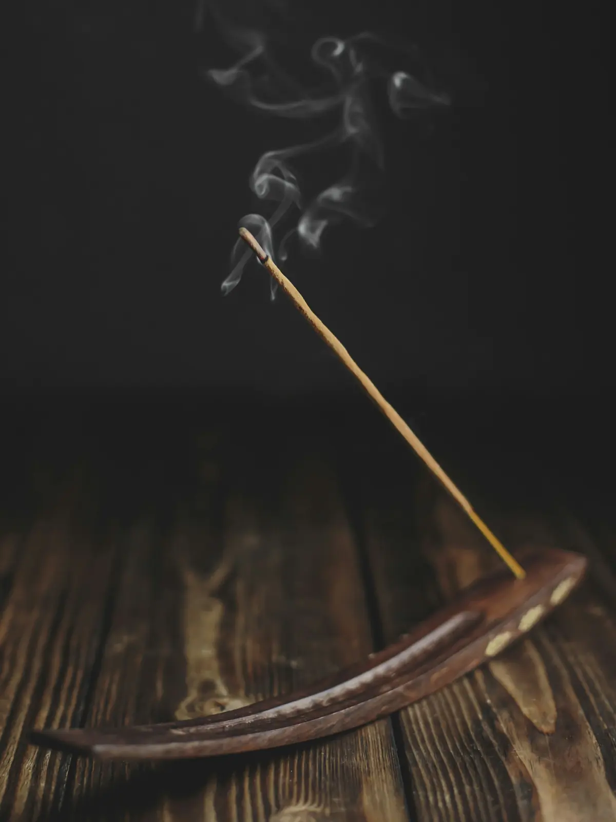 A burning incense stick with a curl of smoke