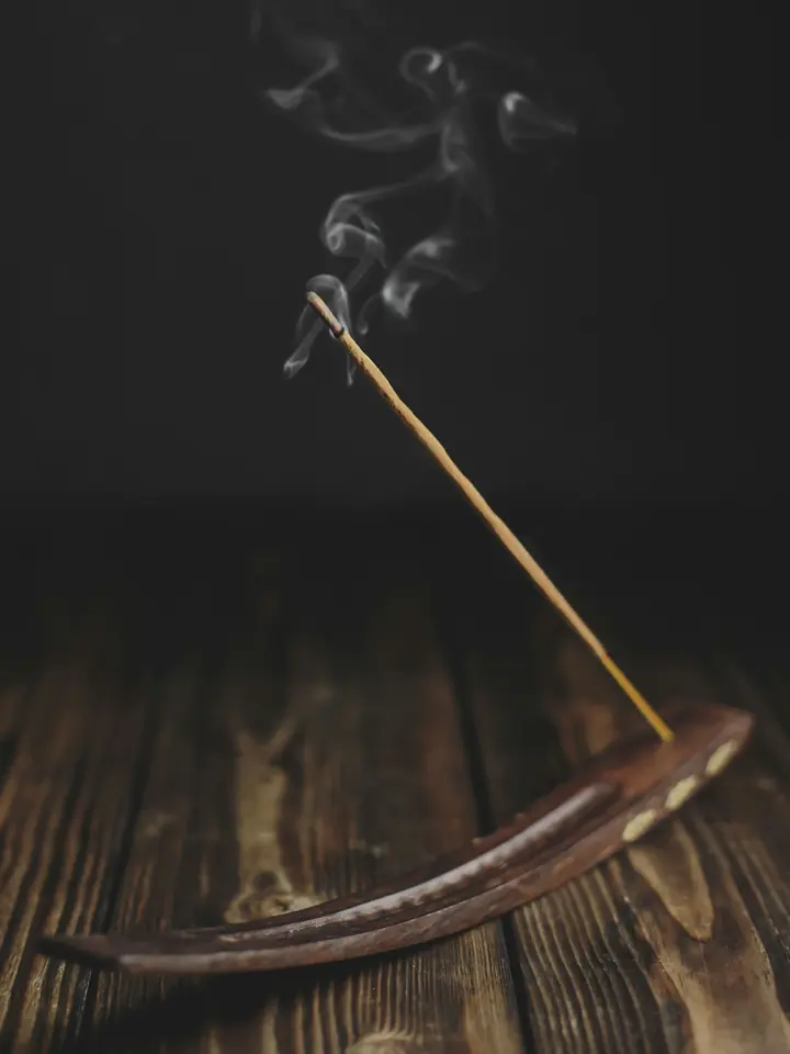 A burning incense stick with a curl of smoke