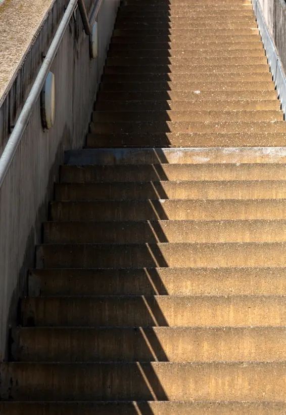 Orange-lit concrete stair in hard sun
