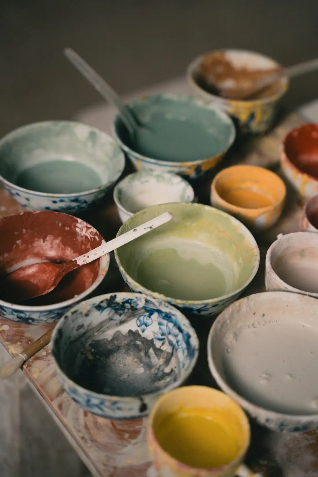 Bowls of colorful glazes and pigments on a table