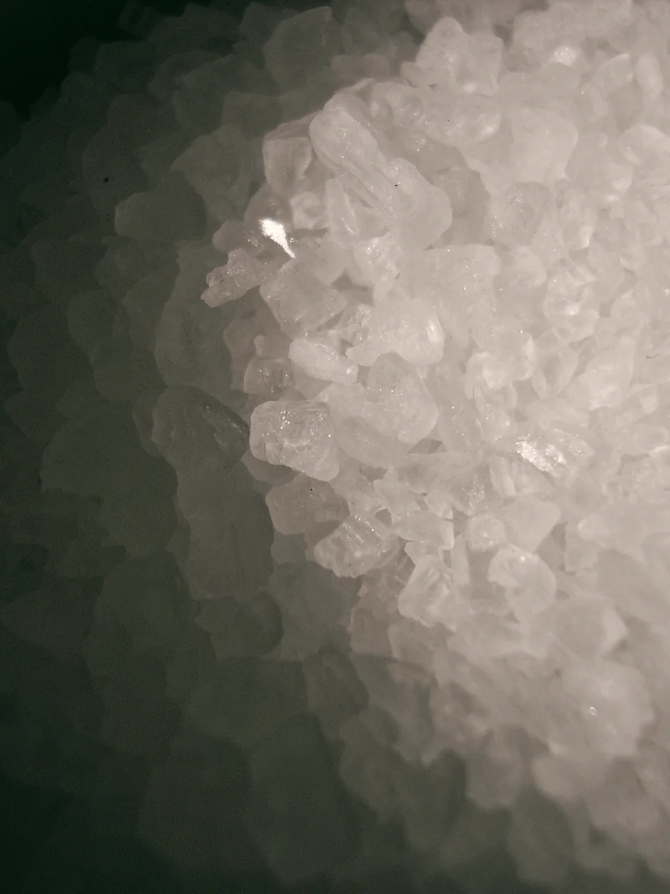 Close-up of white sea-salt crystals piled on a dark surface