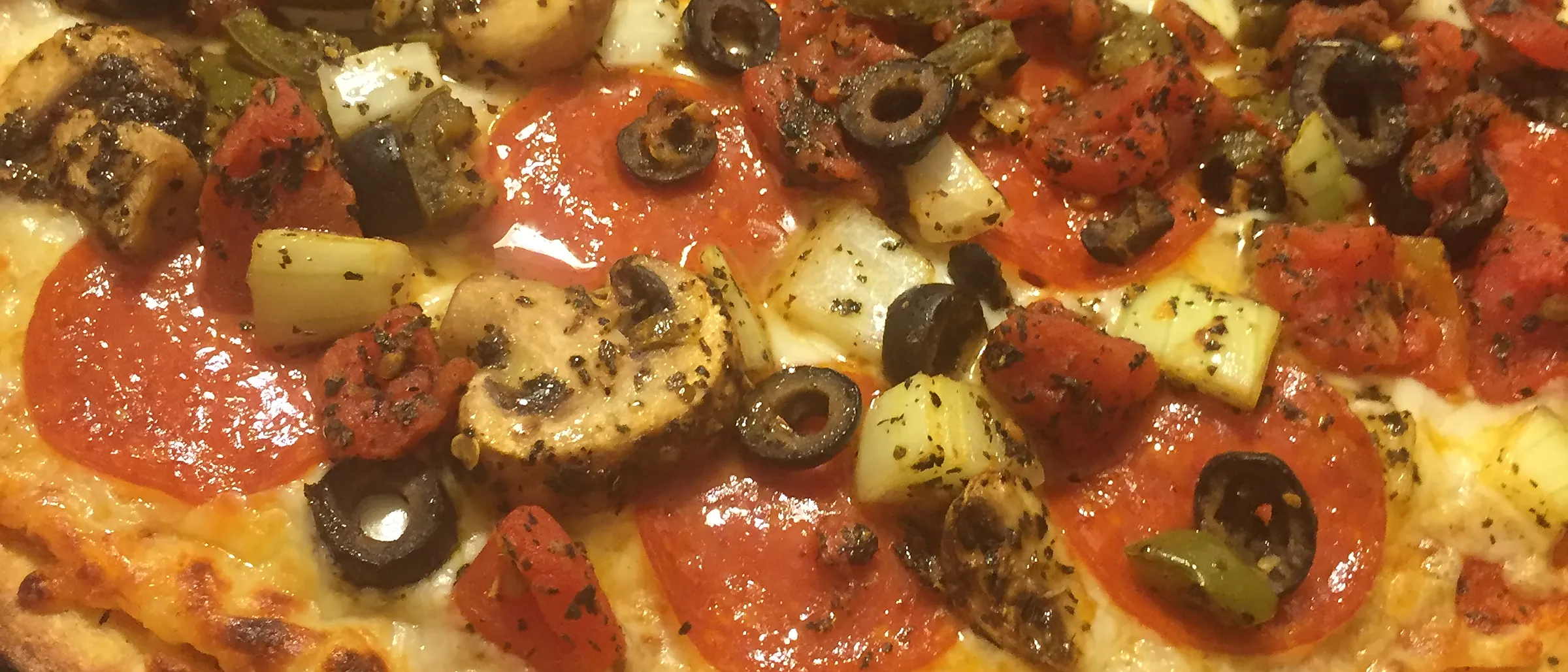 Close-up of a loaded pizza with pepperoni, mushrooms and olives