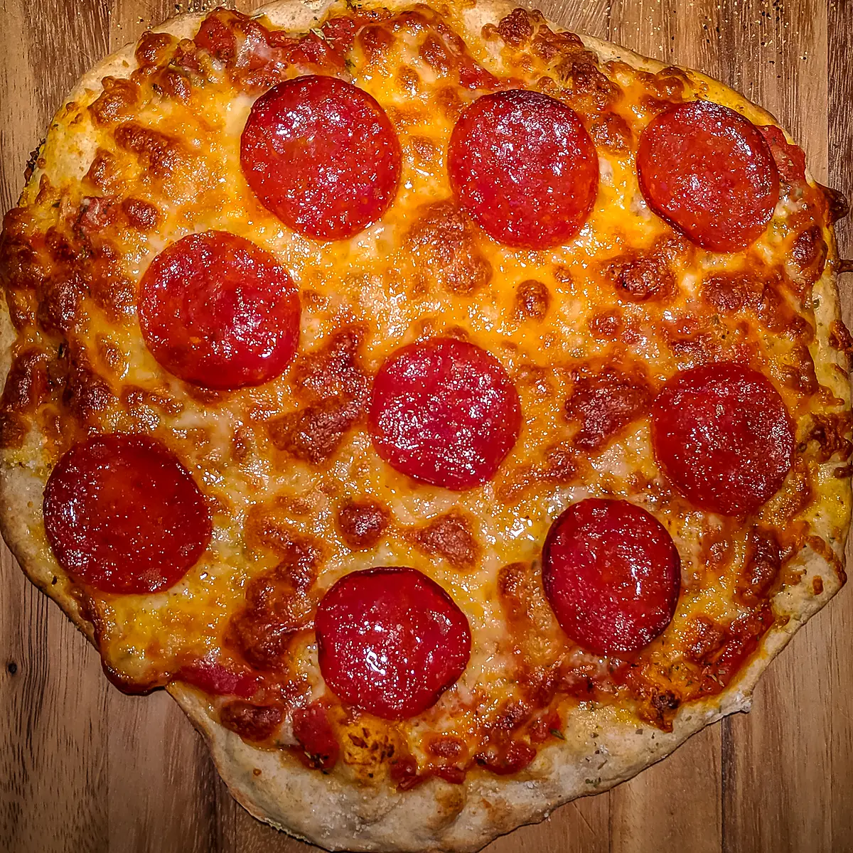 A whole pepperoni pizza with golden, bubbling cheese, seen from above